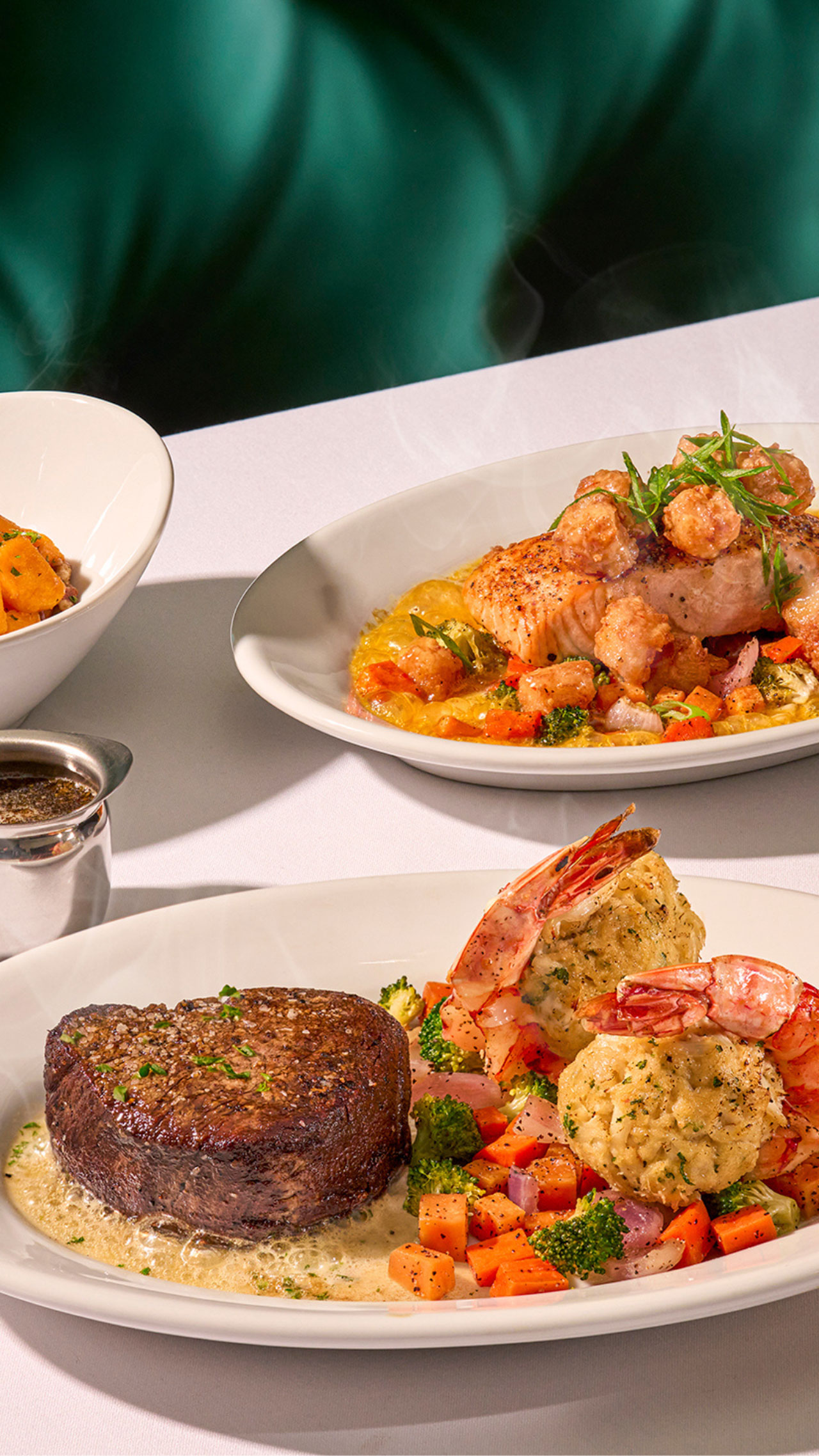 Ruth's Chris CHEF’S Fall SELECTIONS. Three plates from Ruth's Chris' Chef Selected Items served on a table, including the center-cut filet and crab stuffed shrimp, the salmon with bay scallops, and maple-glazed butternut squash. 