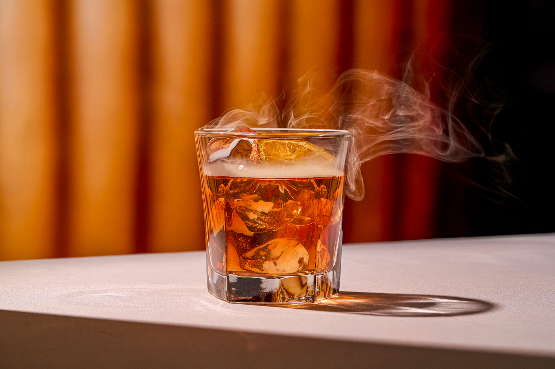 Ruth's Chris' Paper Plane cocktail, featuring woodford reserve bourbon, aperol, and peach, infused with aromatic smoke tableside.